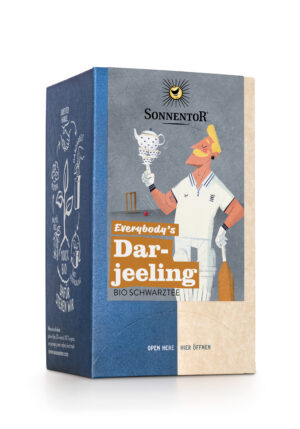 Eine Schachtel Bio-Schwarztee SONNENTOR DARJEELING SCHWARZTEE mit einem kunstvollen Cricketspieler, der eine Teetasse und einen Schläger hält.
