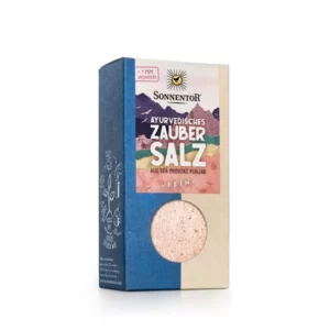 Eine Schachtel SONNENTOR SALZ FEIN AYURVEDE mit Sichtfenster zeigt rosa Salz. Die Verpackung zeigt ein Sonnenlogo und lebendige Designelemente.