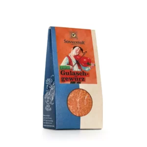 Packung SONNENTOR GEWÜRZMISCHUNG GULASCH mit orange-blauem Design, abgebildet ist eine Person, die eine Tomate hält.