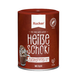 Eine braune Dose der XUCKER HEISSE SCHOKI 11181 Heiße Schokolade mit Xylit, die als zuckerfrei und vegan gekennzeichnet ist, zeigt ein Glas heiße Schokolade mit Schlagsahne und Schokoladenstückchen.