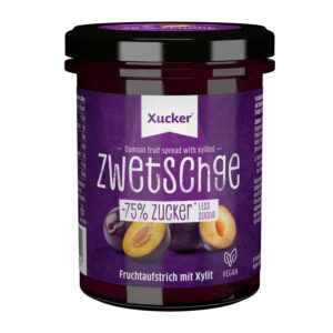 Ein Glas XUCK ZWETSCHGE 10093 Fruchtaufstrich mit Xylit mit der Aufschrift "75 % weniger Zucker" und "Zwetschge", mit Abbildungen von Pflaumen auf lila Hintergrund.
