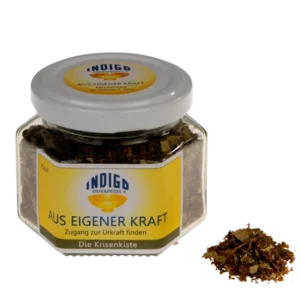 Ein Glas mit der Aufschrift „Indigo Enterprises: AUS EIGENER KRAFT – Zugang zur Urkraft finden“ enthält sichtbare Kräuterinhalte, daneben steht eine kleine Portion der Mischung.