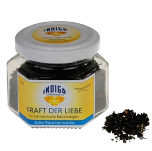 Ein sechseckiges Glasgefäß mit weißem Deckel und der Aufschrift „KRAFT DER LIEBE – für harmonische Beziehungen“ mit dunklem Weihrauch steht neben einem kleinen Haufen Weihrauch.