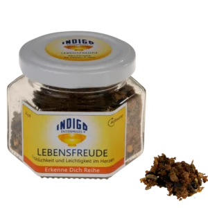 Ein Glas mit der Aufschrift „LEBENSFREUDE – Fröhlichkeit und Leichtigkeit im Herzen“ enthält eine braune, krümelige Substanz, von der etwas verstreut ist.