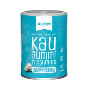 Ein zylindrischer Behälter mit XUCKER XYLIT KAUG FRES 10177 Kaugummi mit einem blauen Etikett, auf dem die Symbole für vegan, TiO2 und BHT frei abgebildet sind.