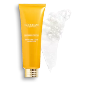 Gelbe Tube LOccitane Immortelle Divine Reinigungsschaum neben einem weißen Schaumabstrich.