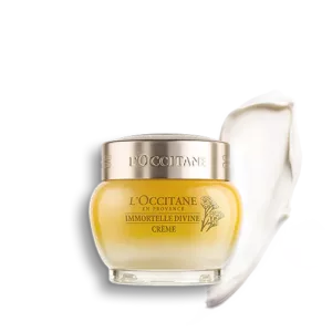 Ein Tiegel LOccitane Immortelle Divine Creme mit einem Klecks Creme daneben.
