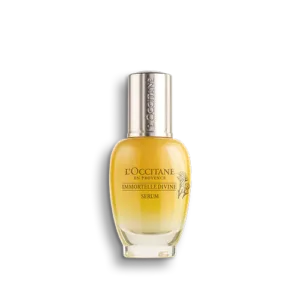 Eine Flasche IMMORTELLE DIVINE SERUM mit klarem Glasboden und goldfarbener Flüssigkeit im Inneren.
