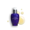 Eine blaue Flasche IMMORTELLE PRECIEUSE SERUM von LOccitane mit einer weißen Pumpe ist von gelben Flüssigkeitströpfchen umgeben.