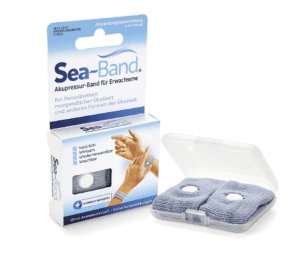 Die Verpackung von SEA-BAND AKUPRESSURBAND und ein geöffnetes Kunststoffetui geben den Blick auf zwei graue Akupressurarmbänder mit weißen Knöpfen zur Linderung von Übelkeit frei.