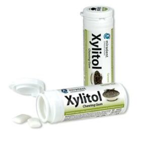 Zwei Behälter MIRADENT XYLIT.GUM GREEN TEA, einer davon geöffnet und mit zwei sichtbaren Kaugummistücken.